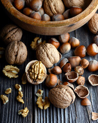 Walnut nuts, kernels and shell in wooden bowl on black stone plate close up. Food photography