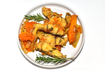 Cod fish with vegetables, ready to eat, lies on a plate, top view.