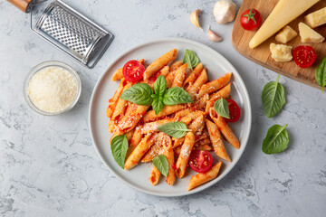 Classic italian pasta penne alla arrabiata with basil and freshly grated parmesan cheese on dark...
