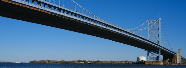 Fototapeta premium Panoramic image of The Ben Franklin Bridge from the philadelphia side built in 1926 spanning between Philadelphia PA and Camden New Jersey on a beautiful blue sky afternoon