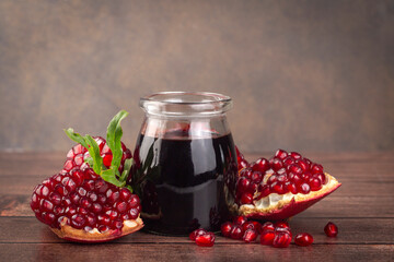 Glass bottle of pomegranate sour sauce with fresh ripe whole and split pomegranate fruit (Turkish...