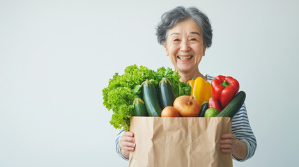紙袋いっぱいに入った野菜を手にする日本人のシニア女性