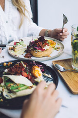 Cropped image of female friends having break on dinner together in cafeteria enjoying healthy veggie food, women satisfied with modern cuisine tasty dishes for healthy nutrition menu and lifestyle