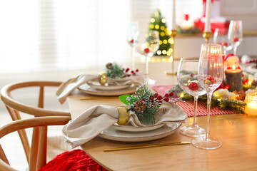 Christmas celebration. Festive table setting with dishware, glasses and decor in room