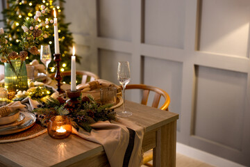 Christmas celebration. Festive table setting with dishware, glasses and decor in room