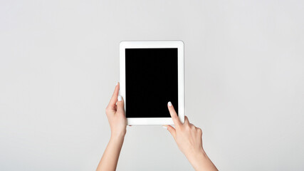 Female hand touching blank screen of tablet computer on white background, mockup for your design. Panorama