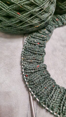 Knitted product from dark threads. Knitting a neck for a sweater with knitting needles.