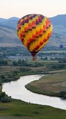 Obraz premium Colorful Hot Air Balloon Soaring Over Scenic River Valley Landscape