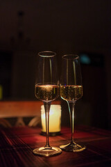 Two elegant wine glasses on a table with a glowing candle