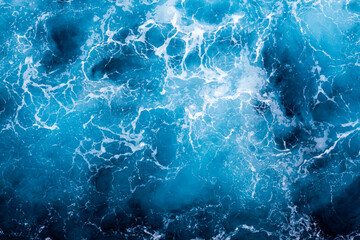 Ocean water surface background. Aerial view of enchanting foamy water. Can be used in covers, packaging, posters, textures, banners, art, and design projects. Captivating nature background image.
