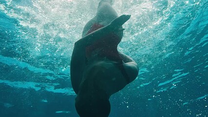 Professional synchronised swimmer performing underwater rotation. Maldives