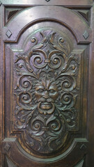 Close up of an intricately carved wooden door with a face