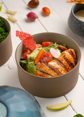 Healthy caesar salad with grilled chicken steak, white wood background