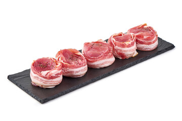 Raw meat medallions wrapped in bacon seasoned with spices, isolated on white background.