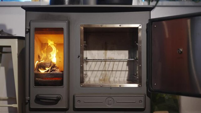 A stove with a fire burning in it. The stove is open and has a rack inside. The fire is orange and yellow