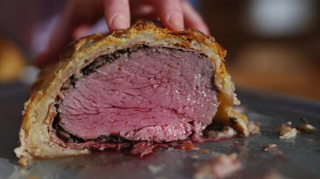 A piece of meat is cut open and is on a plate. The meat is pink and has a lot of fat