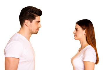 Close up side profile photo funny beautiful she her he him his guy lady stand opposite wait first who take eyes off each other lovely look wear casual white t-shirts outfit isolated yellow background