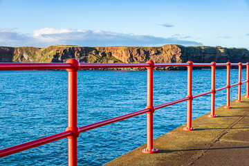 Shiny new red railings on West Pier in the harbour at Eyemouth, Berwickshire, Scottish Borders,...