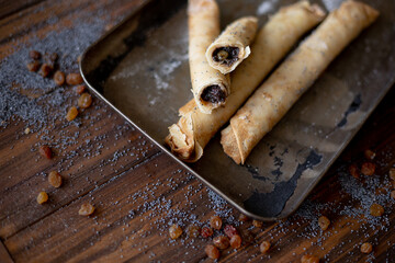 Golden-brown rolled pancakes with a rich poppy seed and raisin filling displayed on a vintage metal...