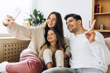 Happy family taking selfie on sofa at home
