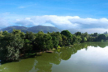 Panoramic view of a tranquil mountain river flowing through a lush valley with towering peaks and clear skies.