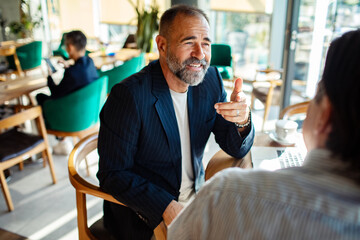 Two businessmen having conversation over coffee in modern cafe