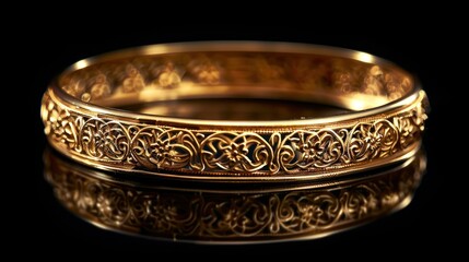 Ornate gold bangle bracelet with intricate Celtic knotwork design, reflecting on a black surface.