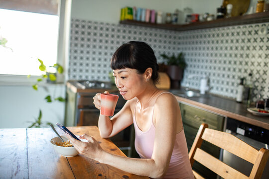 Woman eating healthy breakfast in kitchen at home