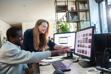 Team collaboration at office desk with dual monitors and brainstorming