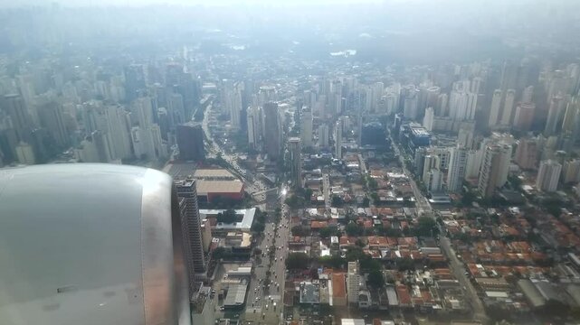 View through the airplane window during a flight over the city of S&atilde;o Paulo, flying close to the buildings arriving at the landing destination, Congonhas airport.