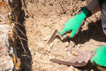 An archaeologist digs away the soil at a dig site using a small trowel for the job.