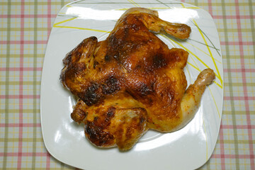 Whole roasted chicken on white plate with plaid tablecloth background