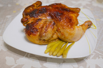 Roasted whole chicken with crispy golden skin served with hot pickled pepper on white plate