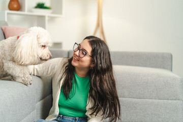 Young woman resting with her white poodle dog in the living room