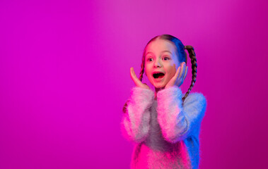 A preteen girl with braided hair shows excitement with a joyful expression, surrounded by neon lights in shades of pink and purple, copy space