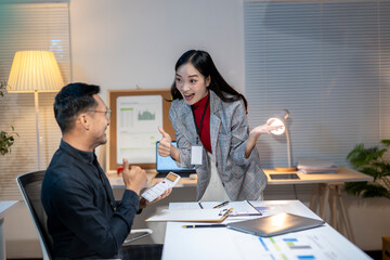 Excited business partners giving thumbs up celebrating success working late