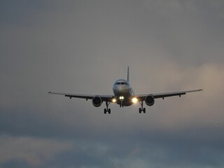 Fototapeta premium Airplane landing under cloudy sky