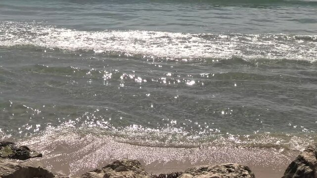 vagues arrivant sur une plage de sable et de rochers