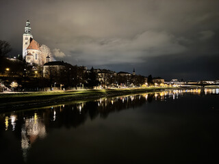Salzburg Austria cityscape at night, along the Salzach River in winter