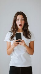Fototapeta premium A surprised young woman holding a smartphone, expressing shock or excitement.