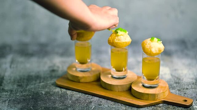 Close up of Indian street food fuchka on a glass with sour spicy water.  Pani puri a chat item in India. 4K indian street food snacks.