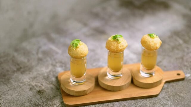 Close up of Indian street food fuchka on a glass with sour spicy water.  Pani puri a chat item in India. 4K indian street food snacks.