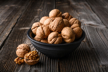 Walnut nuts on black bowl on wooden table close up. Food photography
