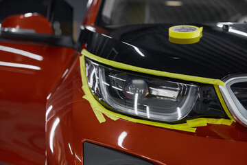 Closeup view on car headlights with attached masking tape