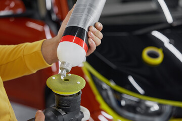 Closeup man worker squeezing out special polishing paste from bottle