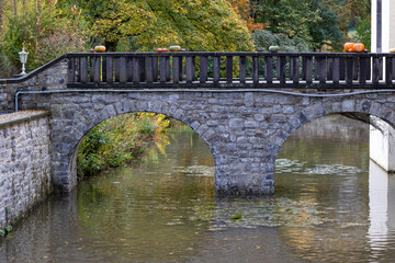 Fototapeta premium A bridge over a river with a stone arch and a few pumpkins on it