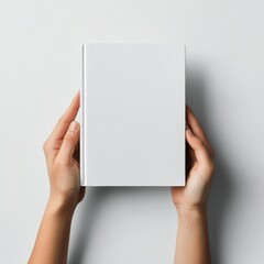 Hands holding a blank book against a plain background in a minimalist setting