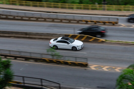 White Mercedes-Benz CLA with panoramic roof in motion, High angle panning shot of a luxury four-door coupe

