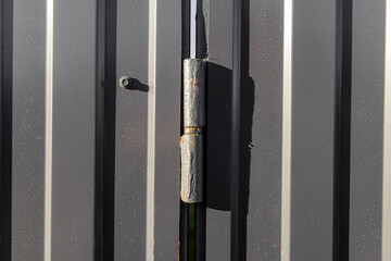 The hinge on the gate of the metal fence. Rusty hinge