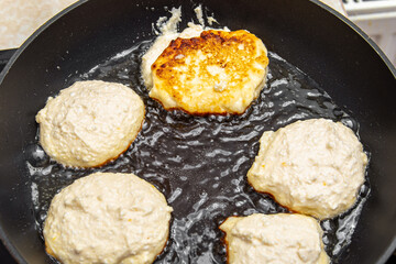 Cheesecakes or pancakes are fried in a frying pan. Sloppy cottage cheese